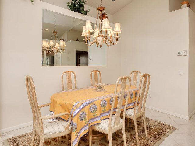 dining space featuring light tile patterned floors, vaulted ceiling, and a notable chandelier