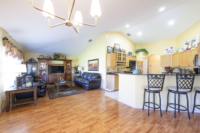 kitchen with a notable chandelier, light hardwood / wood-style floors, kitchen peninsula, and a breakfast bar area