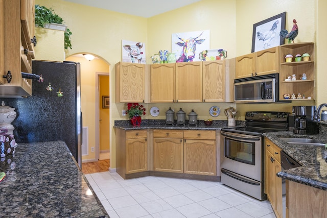 kitchen with dark stone countertops, sink, light tile patterned floors, and black appliances