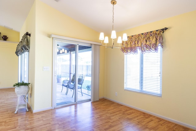 unfurnished room with vaulted ceiling, light hardwood / wood-style flooring, plenty of natural light, and a notable chandelier