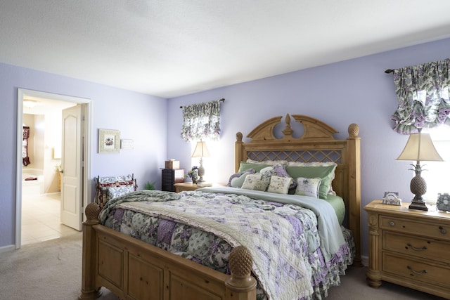 bedroom featuring ensuite bathroom and light colored carpet