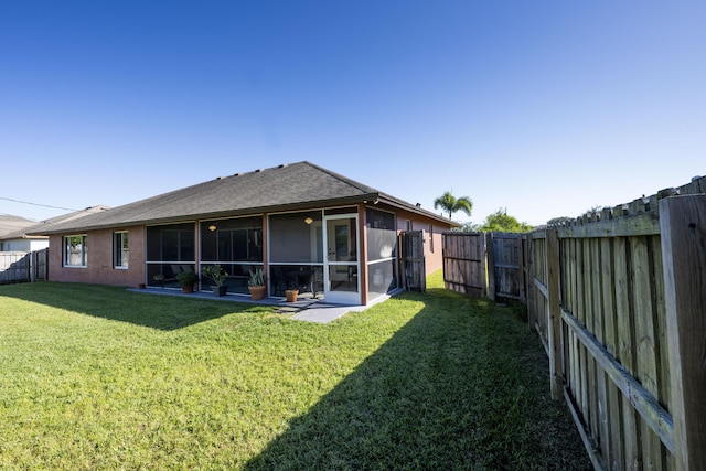 rear view of property featuring a yard and a sunroom