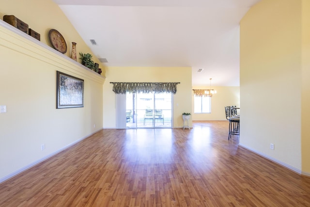 unfurnished room with a chandelier, wood-type flooring, and vaulted ceiling