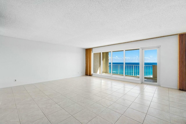 unfurnished room with light tile patterned floors, a water view, and a textured ceiling