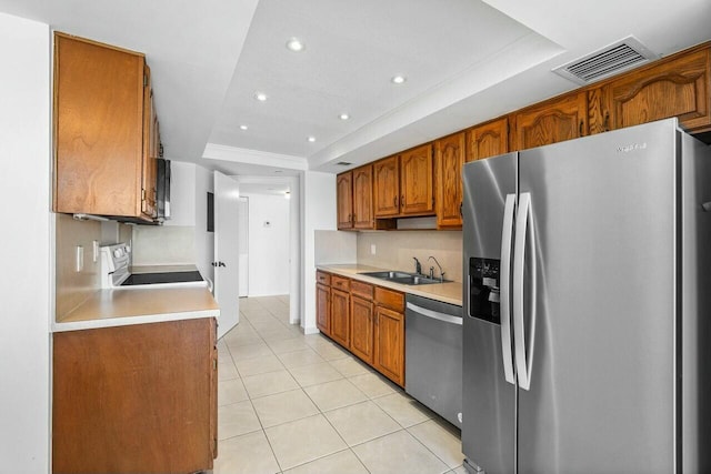 kitchen featuring a raised ceiling, sink, light tile patterned flooring, and appliances with stainless steel finishes