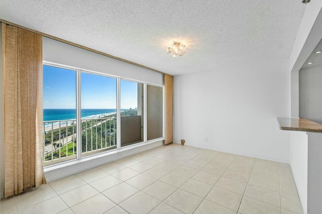 tiled spare room with a water view and a textured ceiling