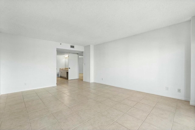 tiled empty room featuring a textured ceiling