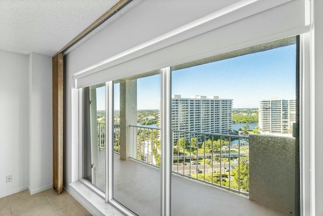 interior space with plenty of natural light, a water view, light tile patterned floors, and a textured ceiling