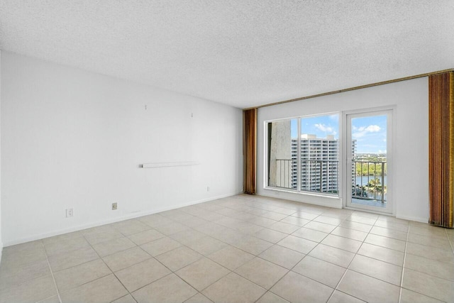 tiled spare room featuring a water view and a textured ceiling