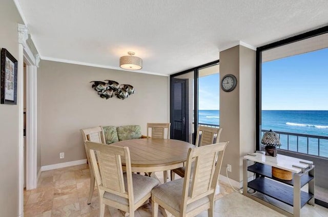 dining space featuring expansive windows, a water view, a textured ceiling, and ornamental molding