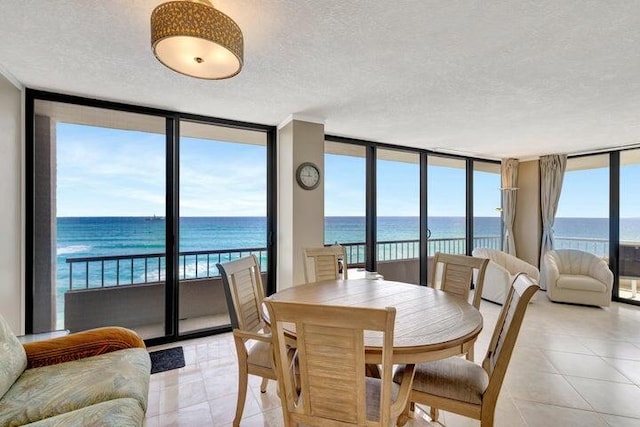 tiled dining room with a textured ceiling, a water view, and plenty of natural light