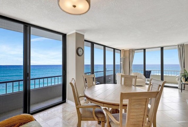 tiled dining room with expansive windows, a water view, a healthy amount of sunlight, and a textured ceiling