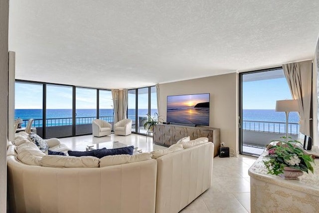 tiled living room with expansive windows, a water view, and a textured ceiling