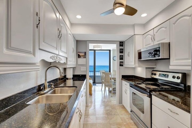 kitchen featuring sink, stainless steel appliances, white cabinets, dark stone countertops, and a water view