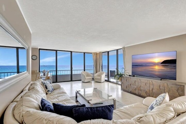 living room with a textured ceiling, a water view, and floor to ceiling windows