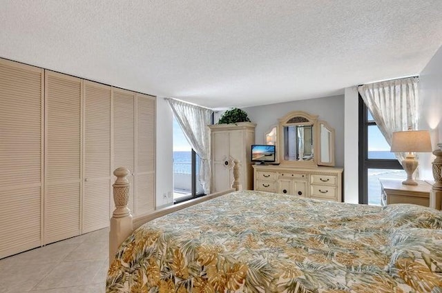 bedroom featuring light tile patterned floors, a textured ceiling, and multiple windows