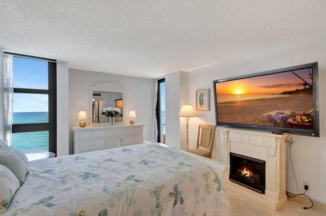 bedroom featuring a textured ceiling, a water view, and light colored carpet