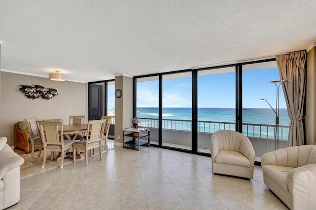 living room featuring expansive windows, a water view, a textured ceiling, and light tile patterned flooring