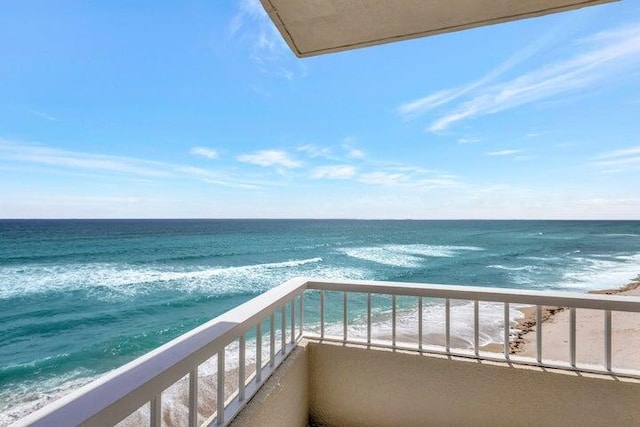 balcony with a water view and a view of the beach