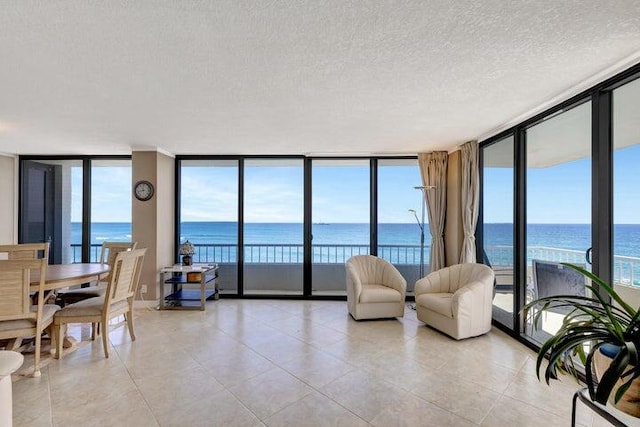 tiled living room with floor to ceiling windows, a water view, and a textured ceiling