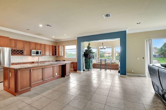 kitchen featuring light tile patterned floors, stainless steel appliances, a kitchen island with sink, and a chandelier