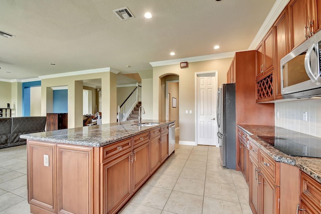 kitchen with sink, an island with sink, decorative backsplash, appliances with stainless steel finishes, and ornamental molding