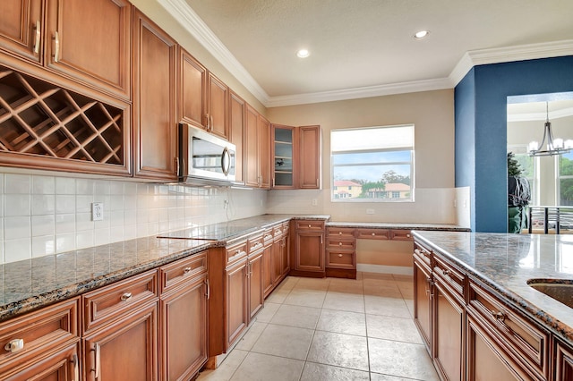 kitchen with a healthy amount of sunlight, dark stone countertops, crown molding, and light tile patterned flooring