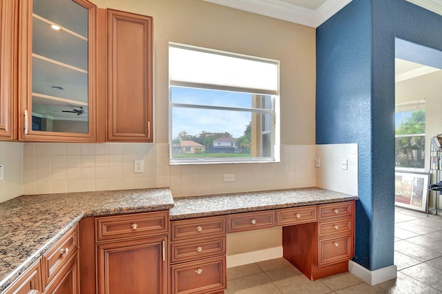 kitchen featuring decorative backsplash, light stone counters, built in desk, and crown molding