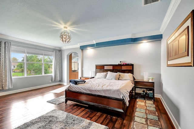 bedroom featuring a textured ceiling, crown molding, and dark wood-type flooring