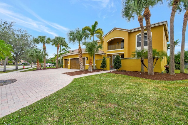 mediterranean / spanish home featuring a front yard, a balcony, and a garage