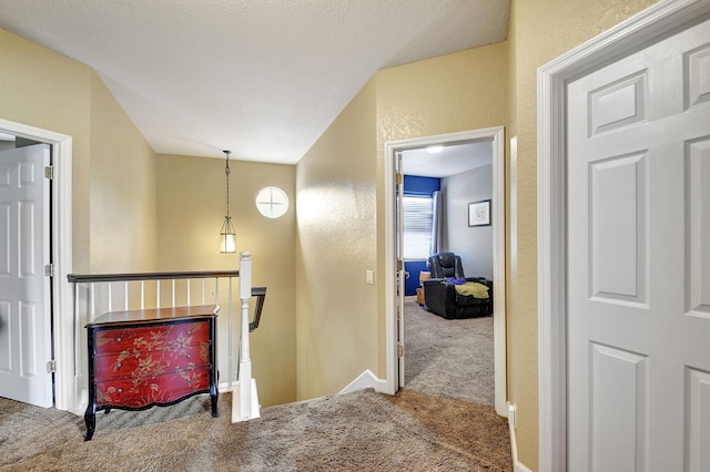 hall with lofted ceiling, carpet floors, and a textured ceiling