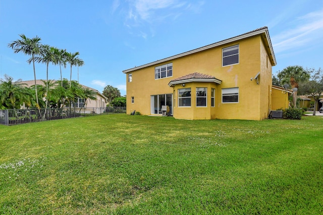 rear view of property featuring central air condition unit and a lawn