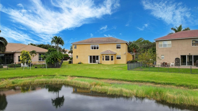 back of house featuring a lawn and a water view