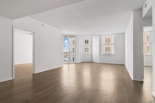 empty room featuring a textured ceiling and dark hardwood / wood-style flooring