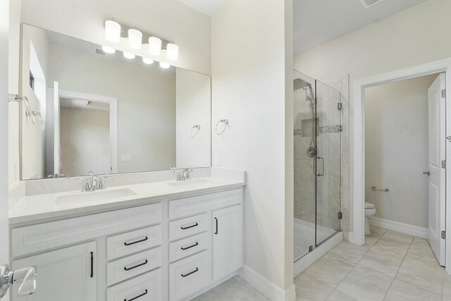 full bathroom featuring double vanity, a shower stall, toilet, and a sink