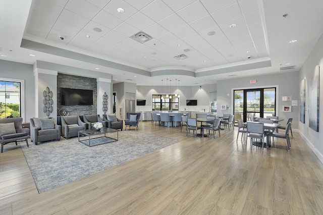 living area with visible vents, a healthy amount of sunlight, and a tray ceiling