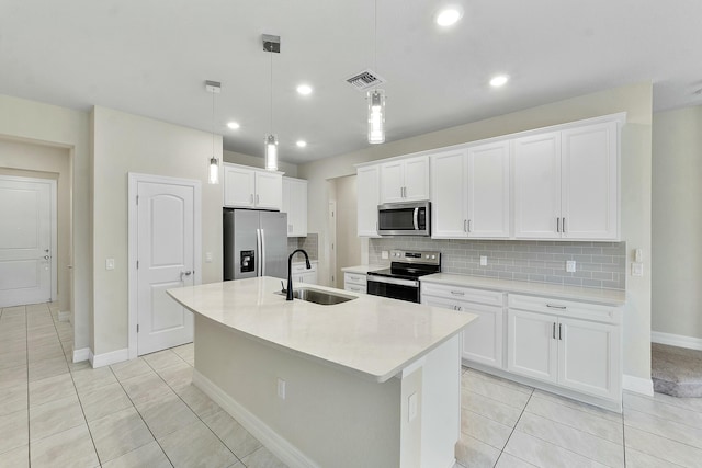 kitchen featuring white cabinetry, sink, hanging light fixtures, stainless steel appliances, and a kitchen island with sink