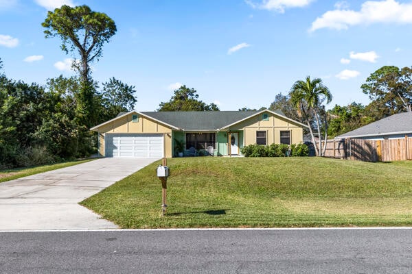 single story home featuring a garage and a front lawn