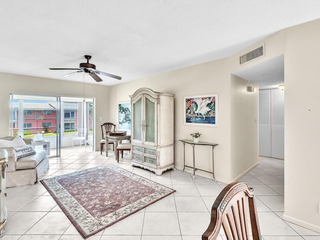 living room with a textured ceiling, ceiling fan, and light tile patterned flooring