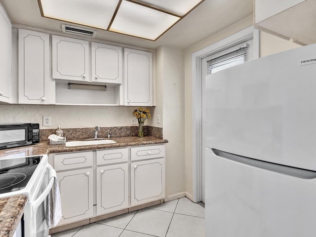 kitchen featuring white cabinetry, sink, dark stone counters, white appliances, and light tile patterned flooring