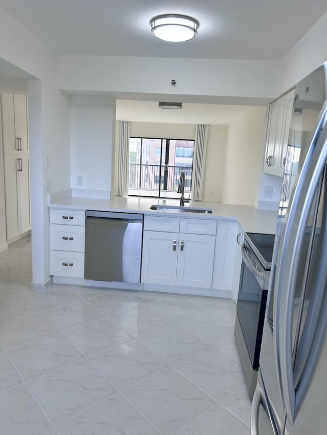 kitchen with kitchen peninsula, white cabinetry, sink, and stainless steel appliances