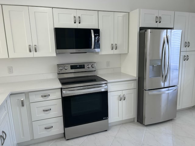 kitchen with white cabinets, stainless steel appliances, and light stone counters