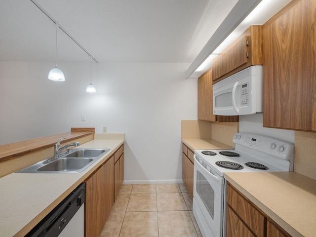 kitchen with sink, light tile patterned flooring, hanging light fixtures, and white appliances