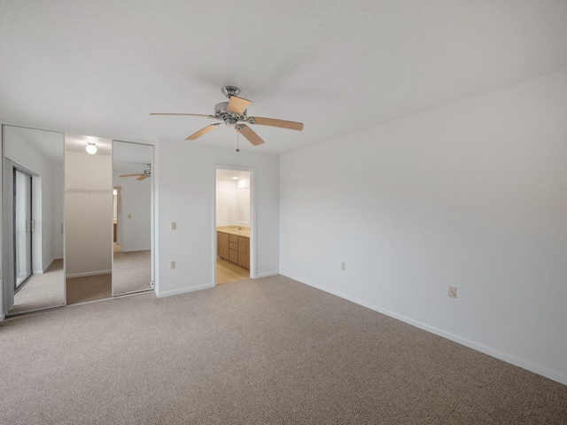 unfurnished bedroom featuring light carpet, connected bathroom, a closet, and ceiling fan