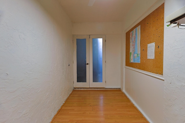 corridor with wood-type flooring and french doors