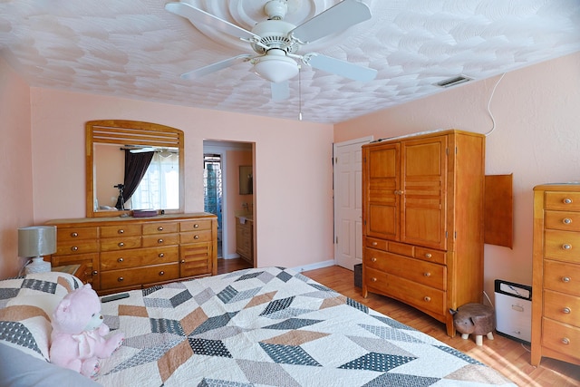 bedroom with connected bathroom, ceiling fan, and light hardwood / wood-style flooring