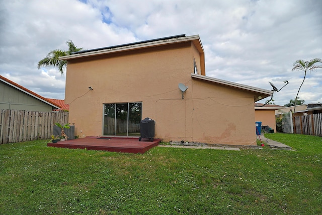 rear view of property featuring a lawn and a wooden deck