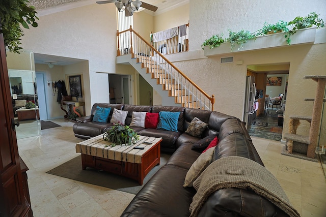 living room with ceiling fan, ornamental molding, and a high ceiling