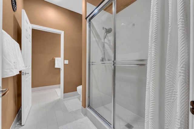 bathroom featuring tile patterned flooring, toilet, and a shower with shower door