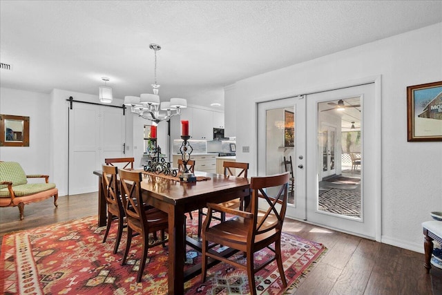 dining room featuring french doors, an inviting chandelier, a textured ceiling, and hardwood / wood-style flooring